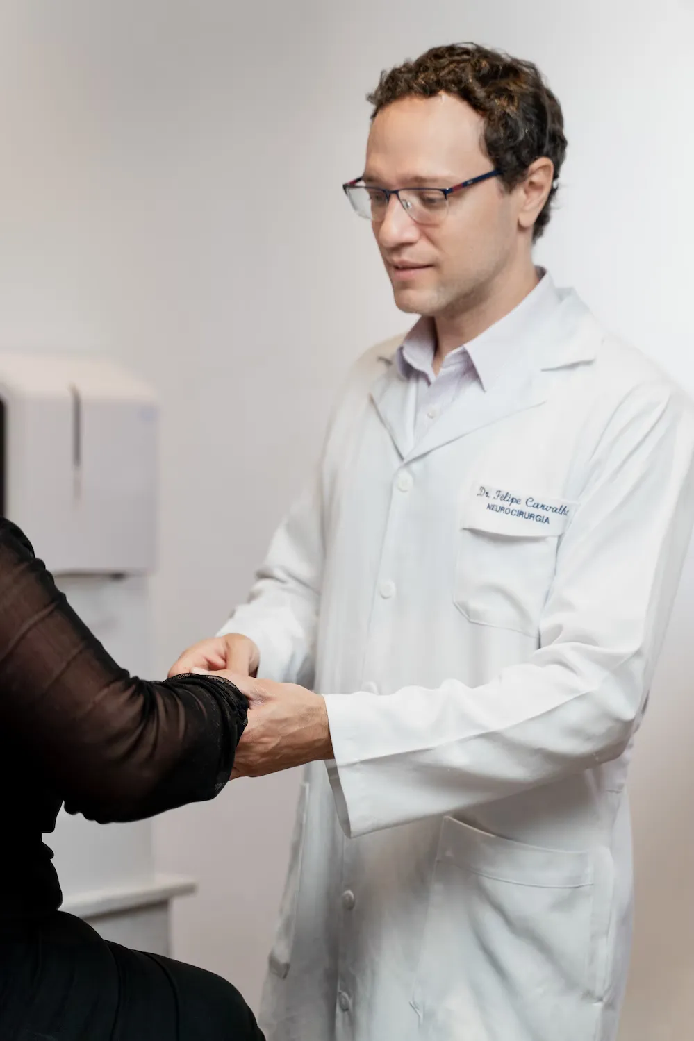 Dr. Felipe Carvalho, de jaleco, durante exame físico no consultório
